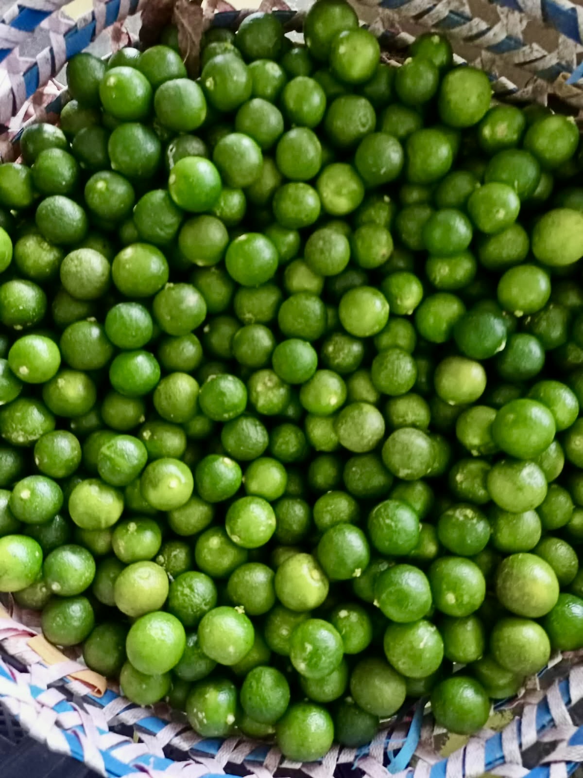 Close-up of fresh green Philippine calamansi in a woven basket, from Island Mango Ireland.