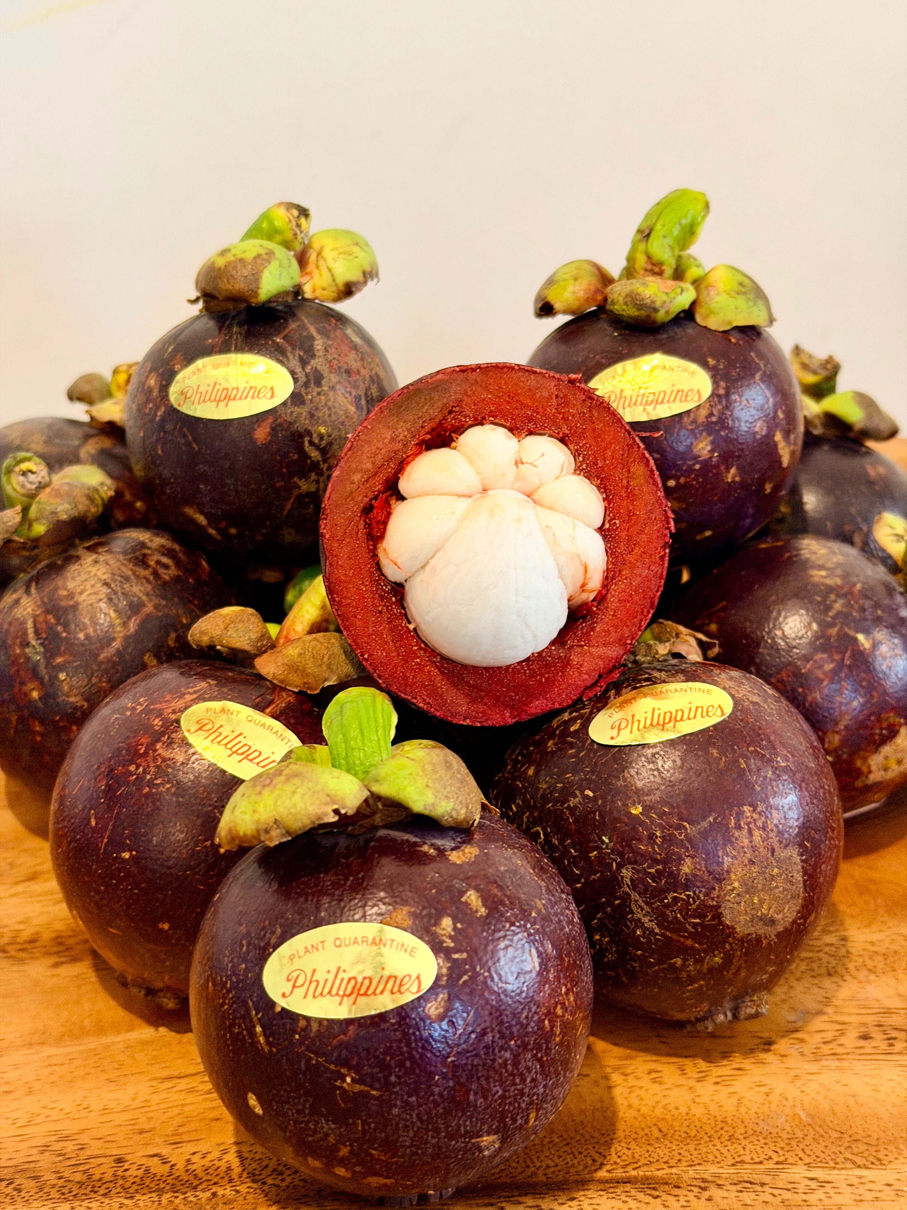 Fresh Philippine mangosteen with one cut open showing white flesh, with Philippines quarantine stickers, from Island Mango Ireland.