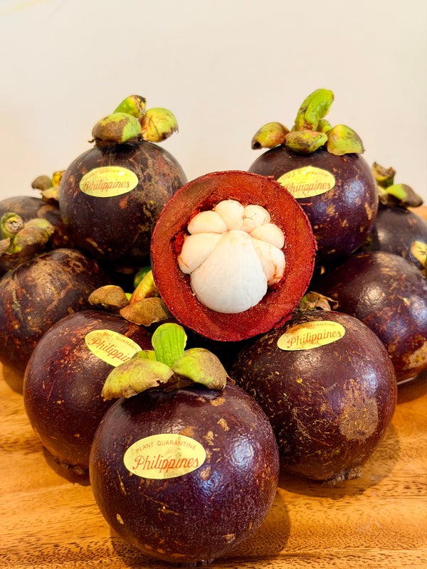 Fresh Philippine mangosteen with one cut open showing white flesh, with Philippines quarantine stickers, from Island Mango Ireland.